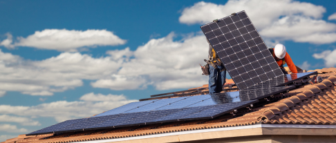 Workers installing solar panels on a tile roof